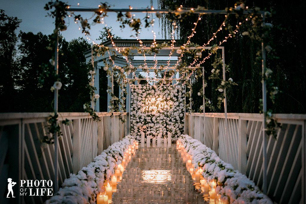 Shine Bright Like A Diamond – Brücke mit Lichterketten, weißer Blumenwand und Kerzenpfad