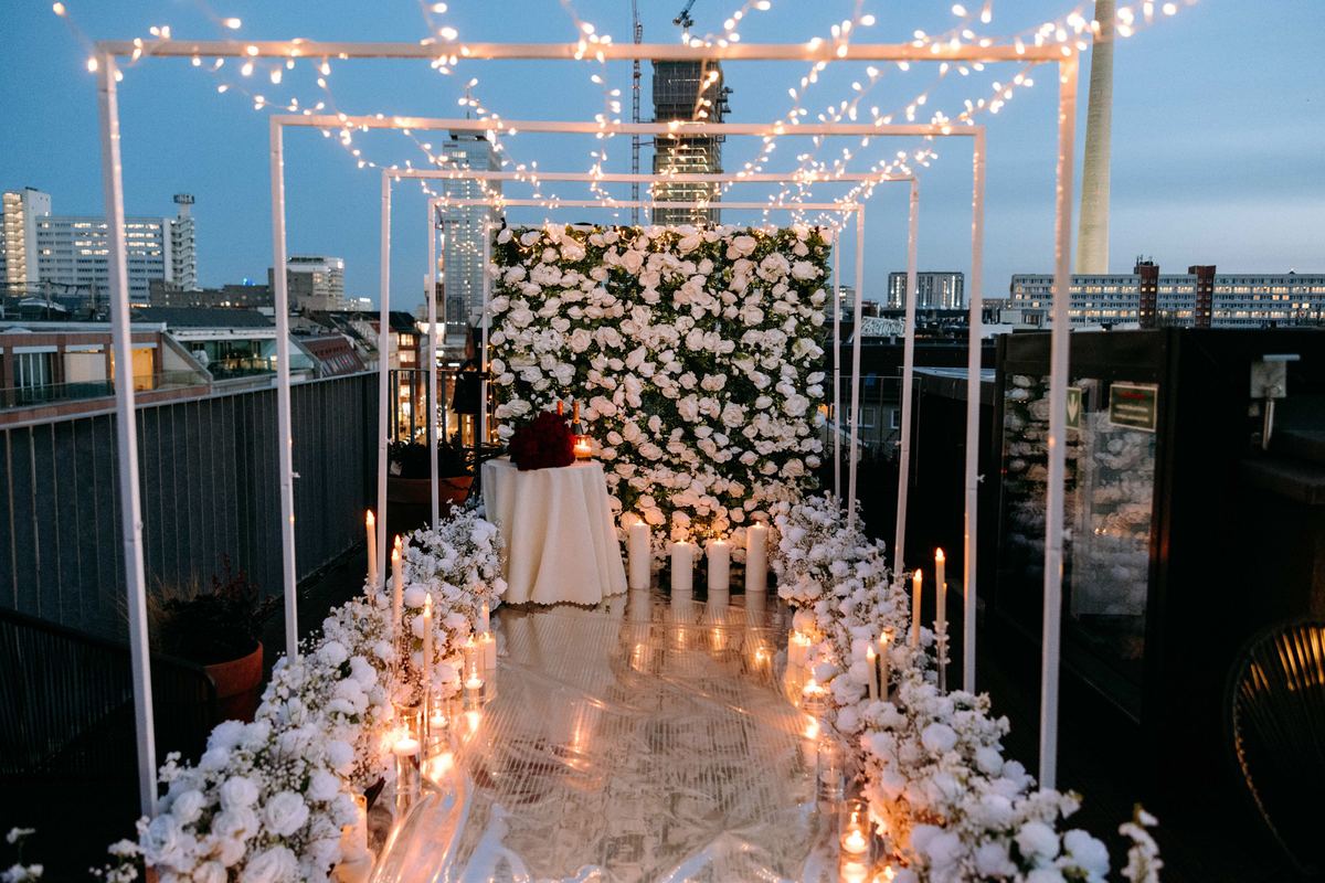 Heiratsantrag Berlin Rooftop weiße Blumenwand Lichterketten Tunnel Kerzen